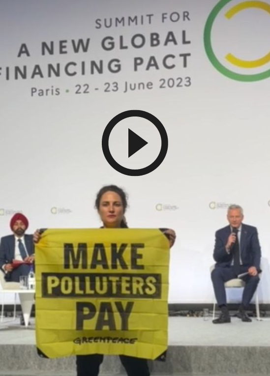 Activiste de Greepeace déployant une bannière "Make polluters pay" devant Bruno Le Maire